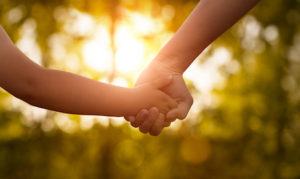 A parent and child hold hands while going through a child custody case