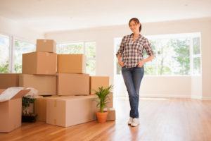 A women who is selling her house in the real estate market standing by packed boxes
