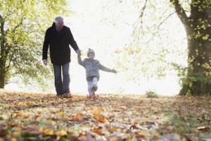 Grandfather walking outdoors with grandson in autumn after divorce agreement