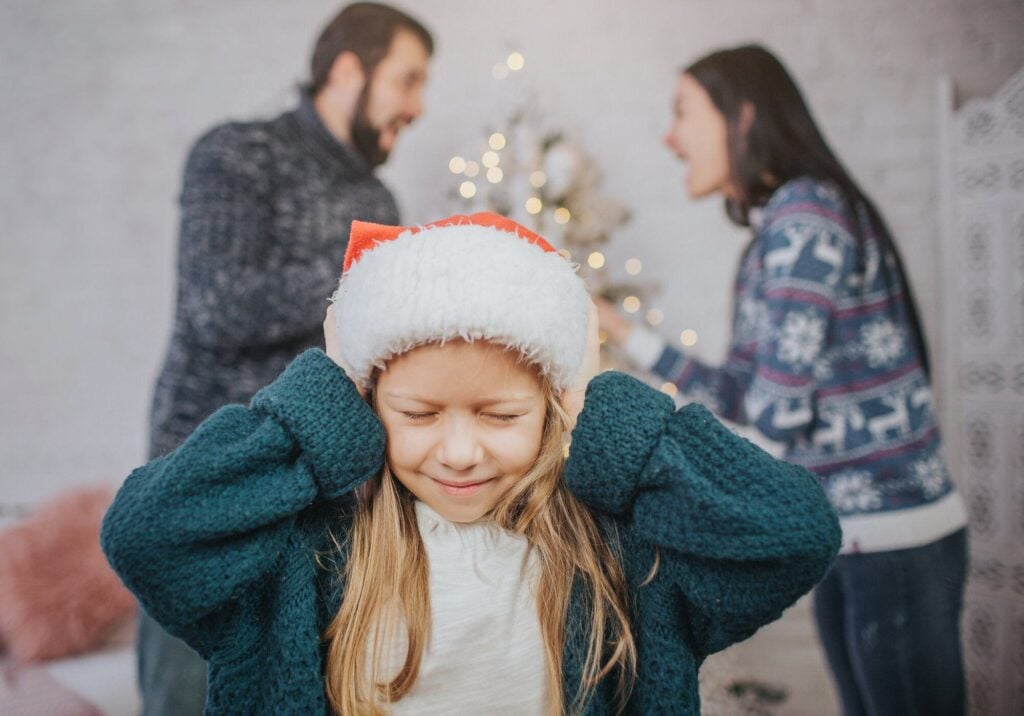 Child covering ears while parents fight