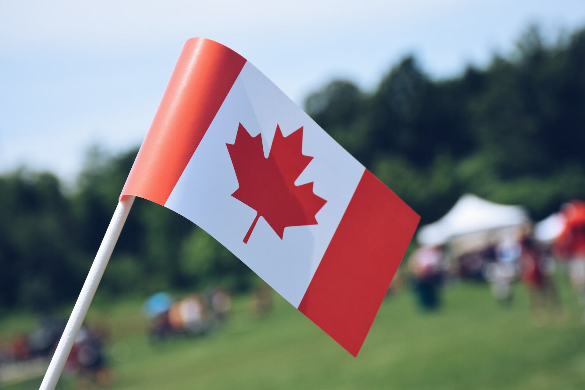A Canadian flag with blurred fairgrounds in the background